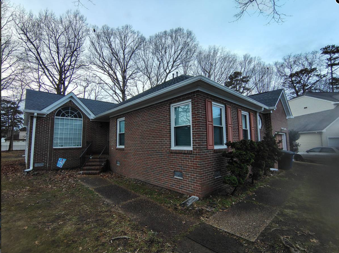Brick home with a new roof, white trim and downspouts