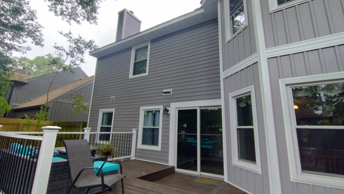 Rear of a home with gray siding and a white deck railing