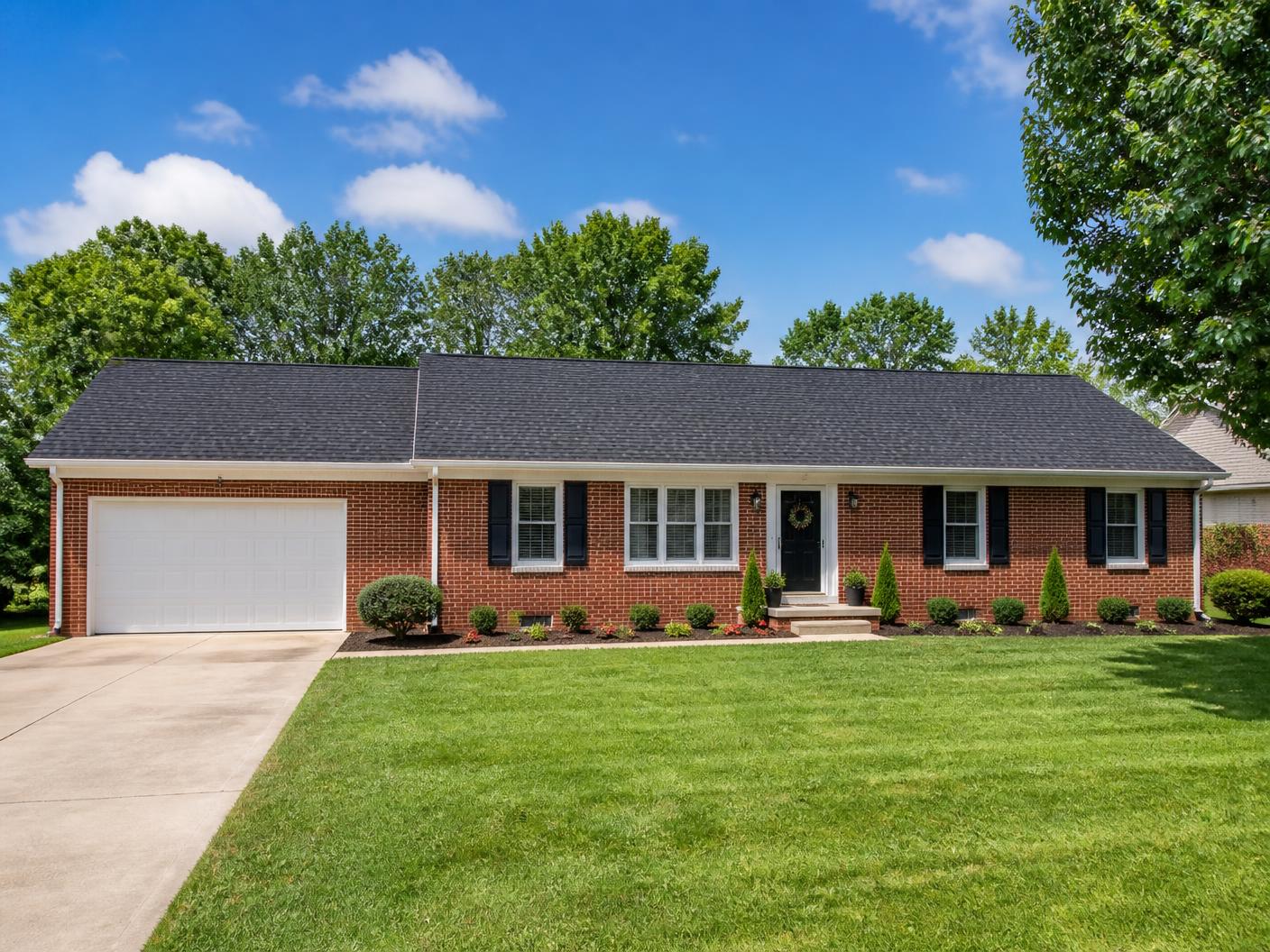 Illustrative photo of a brick home with a new dark shingle roof and white trim